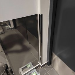 Tyzon Victor Tyszlewicz - Nowoczesna łazienka z szarą glazurą i dużym lustrem, odbijającym fragment podłogi. Widoczne detale wykończenia i minimalistyczny design.
