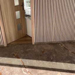 Primebud - Nowoczesne wykończenie wnętrza: drewniane lamele ścienne, marmurowe płytki podłogowe i otwarte drzwi z przeszkleniami. Minimalistyczny design.