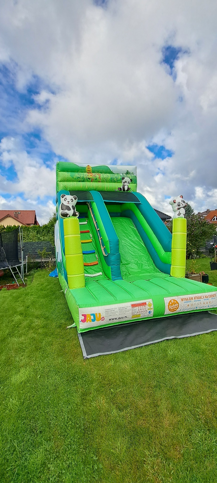 Zielony dmuchany zamek ze zjeżdżalnią, ozdobiony motywem pand, ustawiony na trawniku. Widoczne logo 'JAJU.pl' i hasło 'Wynajem atrakcji na eventy'.