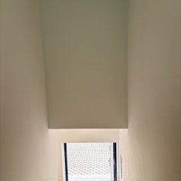 KS - Montaż u Wykończenia - Wnętrze po malowaniu: gładkie, jasne ściany w odcieniach bieli, widok na zewnątrz przez otwarte drzwi. Minimalistyczny design, świeżo odnowione pomieszczenie.