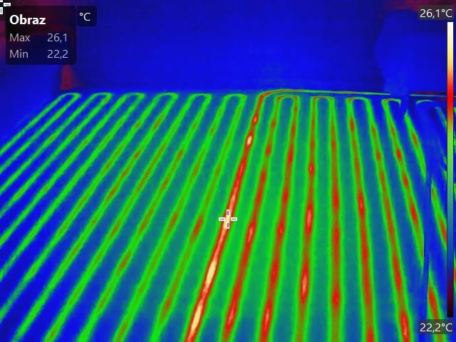Termowizyjne zdjęcie ogrzewania podłogowego w trakcie działania, ukazujące rozkład temperatury w rurach. Widoczne wartości minimalne i maksymalne temperatury.