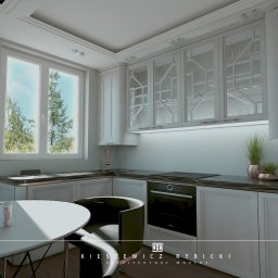 Kristobal Design - Elegancka, jasna kuchnia z białymi szafkami, czarnym blatem i okrągłym stołem. Widoczne detale: szklane fronty szafek, dekoracyjny żyrandol i roślina w doniczce.