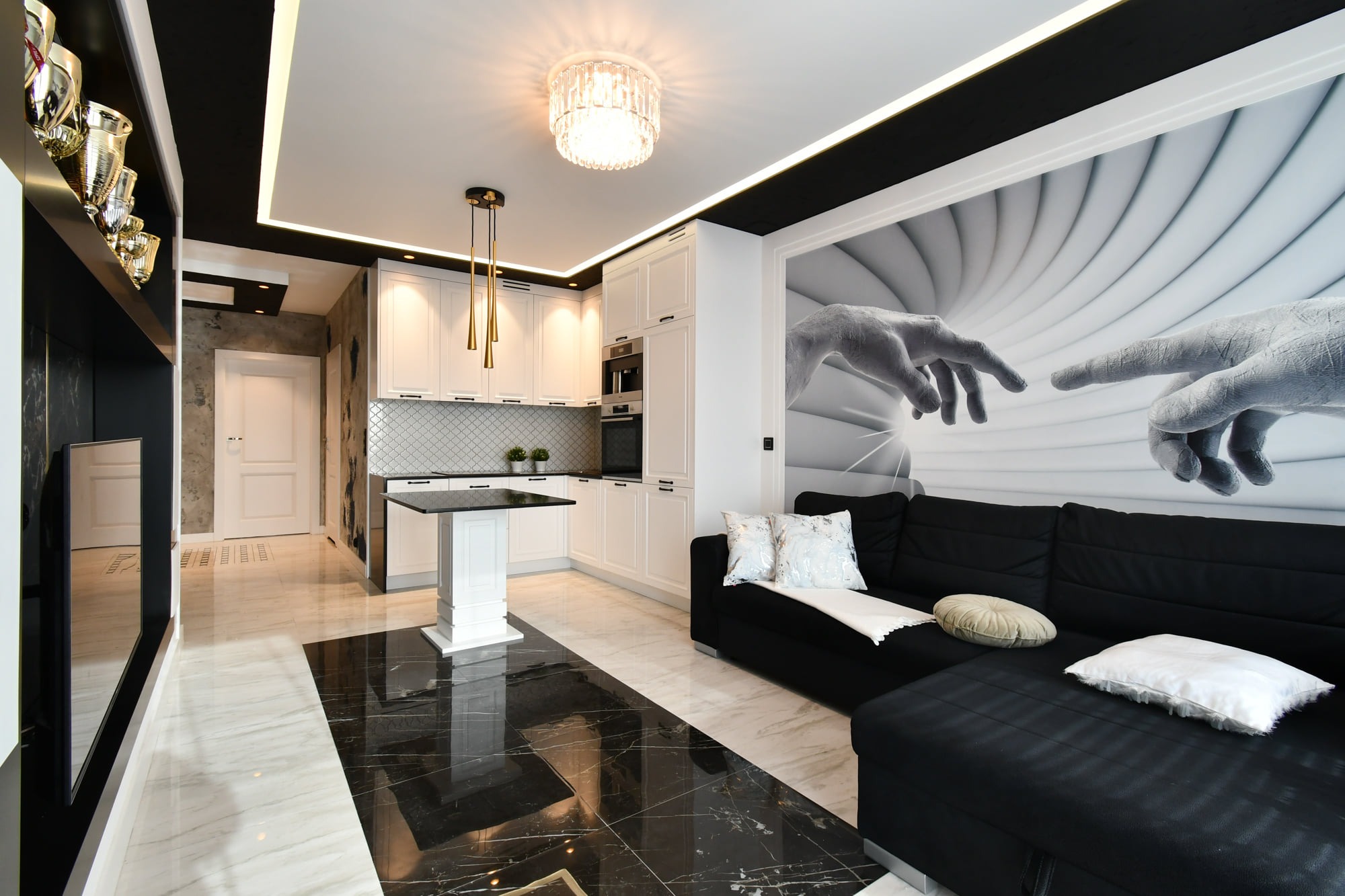Nowoczesne wnętrze z aneksem kuchennym w Torzymiu. Czarno-biała kolorystyka, marmurowe podłogi, designerskie oświetlenie i grafika na ścianie nadają elegancji.