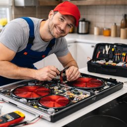 SERWIS AGD - Rafał Sulma - Uśmiechnięty serwisant w czerwonej czapce naprawia płytę indukcyjną z czerwonymi grzałkami. Widoczna skrzynka z narzędziami i miernik.