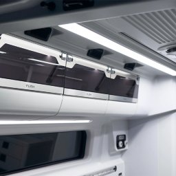 KG Special Performance - Wnętrze pojazdu specjalnego z oświetleniem LED i schowkami z napisem 'PUSH'. Widoczne gniazda i elementy wyposażenia. Czyste, białe wykończenie.