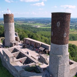 DRONAM dron*foto*film - Panorama zamku w Chęcinach z lotu ptaka, dwie wieże, dziedziniec z turystami, otoczenie zieleni i krajobrazu. Ujęcie z drona w słoneczny dzień.