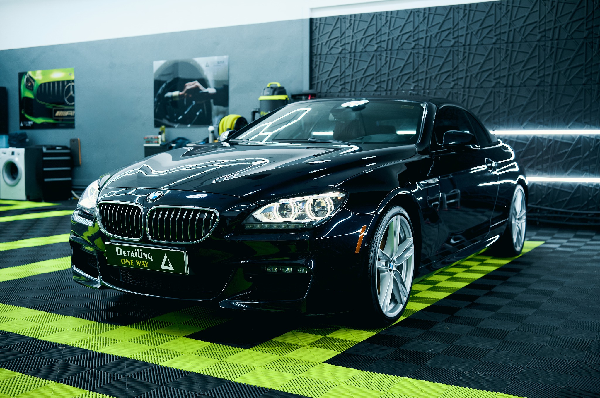 Błyszczący, czarny BMW serii 6 Cabrio na podłodze w szachownicę w studiu detailingowym. Widoczne logo 'Detailing ONE WAY'.