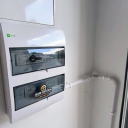 GAW-System - Biała skrzynka elektryczna EPN Elegant z instalacją w Kobyłce. Widoczne przewody i logo firmy Gaw-System. Ujęcie z bliska, oświetlenie dzienne.