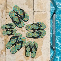 ID STUDIO - Klapki z geometrycznym wzorem w odcieniach niebieskiego i żółtego, ułożone na krawędzi basenu w Krakowie. Widoczne odbicia światła w wodzie.