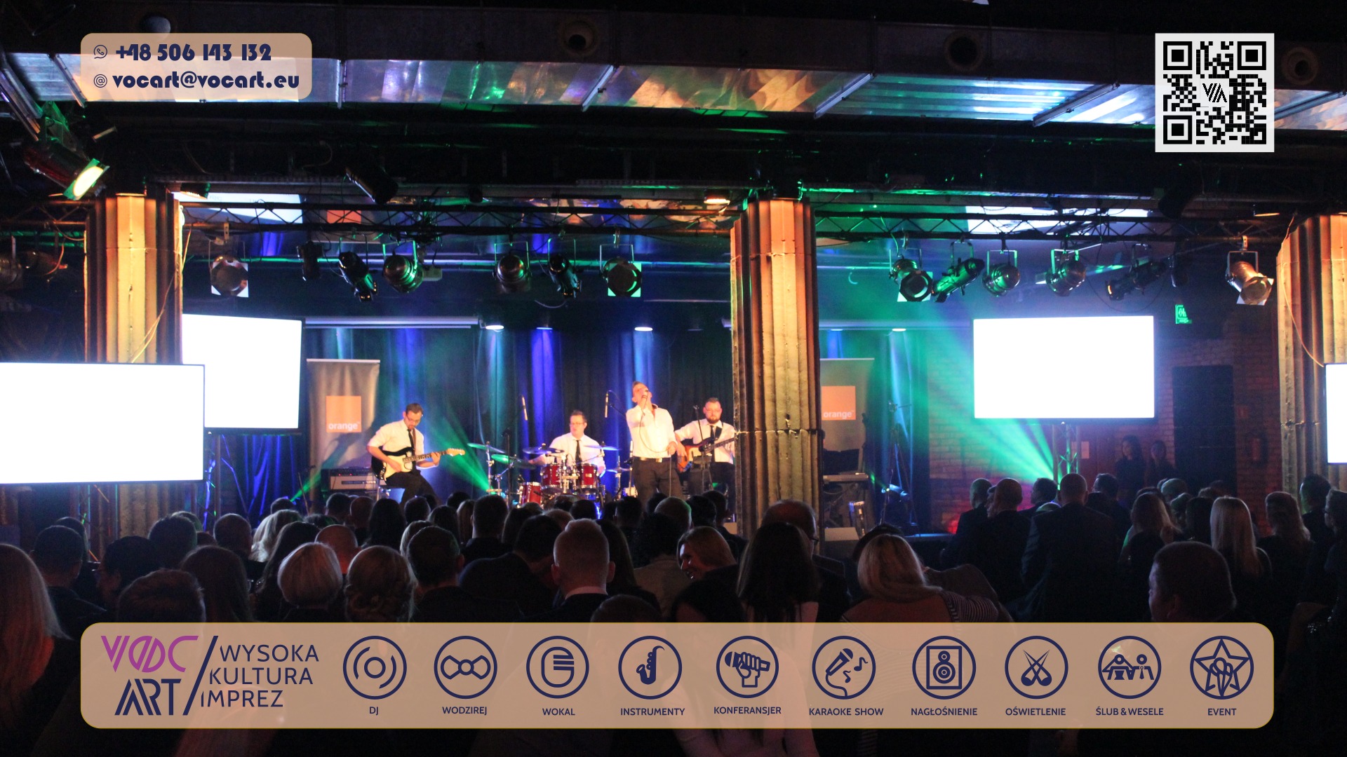 Zespół muzyczny na scenie, oświetlenie sceniczne, publiczność. Widoczne instrumenty i ekrany. Kolorowe światła tworzą atmosferę koncertu.