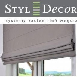 MALMAX Patryk Motyl - Szara roleta rzymska zamontowana w oknie, widok z bliska. Stonowana kolorystyka i delikatne fałdy tkaniny. Usługa montażu w Warszawie.