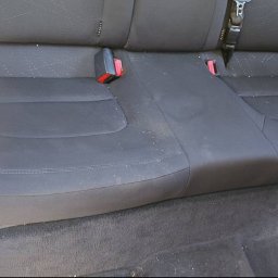 KingClean Expert - Zabrudzona tylna kanapa samochodu przed czyszczeniem. Widoczne okruchy i plamy na ciemnej tapicerce. Ujęcie z bliska, z napisem 'Przed' w lewym górnym rogu.