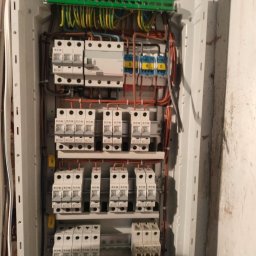 Valentyn Hoidenko - Rozdzielnica elektryczna z bezpiecznikami EATON, okablowaniem i listwami zaciskowymi wewnątrz białej obudowy, zamontowana na ścianie. Widoczne oznaczenia i numery przewodów.