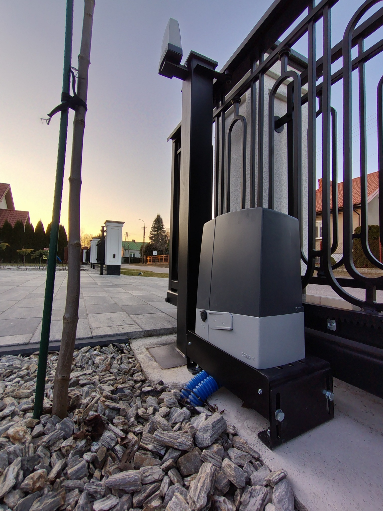 Zamontowany napęd do bramy posesyjnej CAME w Zawistach Nadbużnych, widoczny z bliska na tle ozdobnego kamienia i ogrodzenia. Ujęcie z dołu podkreśla solidność instalacji.