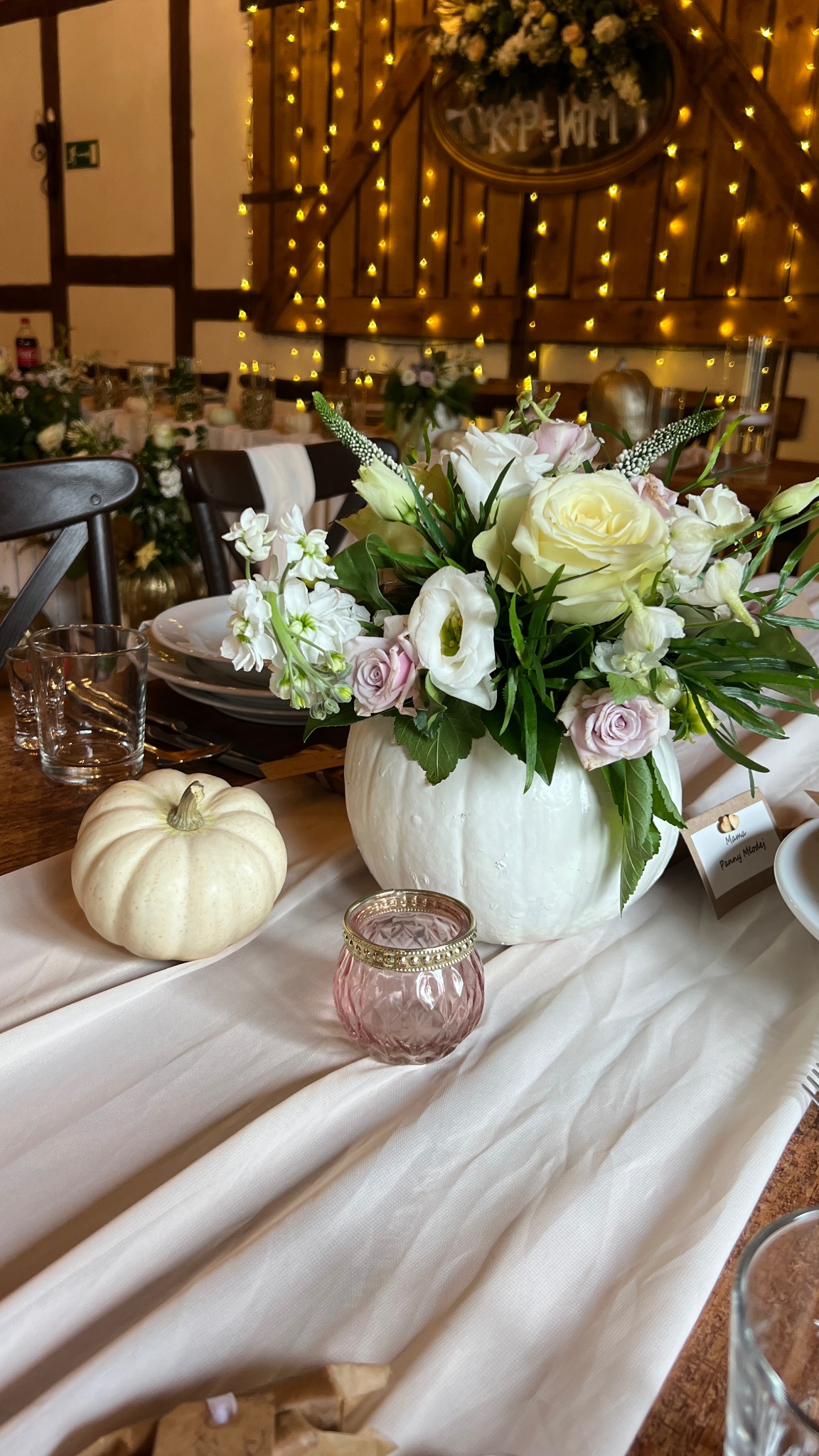 Dekoracja stołu z dyni i kwiatów na przyjęciu w Koszalinie. Romantyczny wystrój sali z lampkami, idealny na wesele lub inną uroczystość.