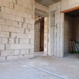 Nikodem Nowakowski - Surowy stan: instalacja elektryczna w peszlach na podłodze, kable w ścianie, ściany z betonu komórkowego, widok na wnętrze w trakcie budowy.