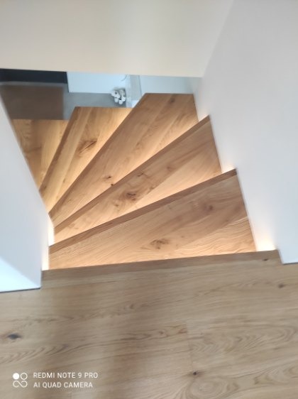 Nowoczesne schody drewniane z subtelnym oświetleniem LED, widok z góry. Jasne drewno i minimalistyczny design tworzą eleganckie połączenie.