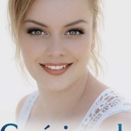 Czyścioszek Usługi Sprzątające - Portret uśmiechniętej blondynki z zielonymi oczami, w białej bluzce z koronką, na jasnym tle. Widoczne delikatne cieniowanie makijażu.