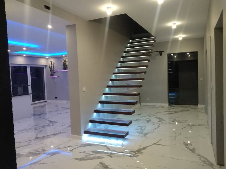 Nowoczesne schody z podświetleniem LED i marmurową podłogą w przestronnym wnętrzu. Minimalistyczny design, eleganckie wykończenie, subtelne oświetlenie.