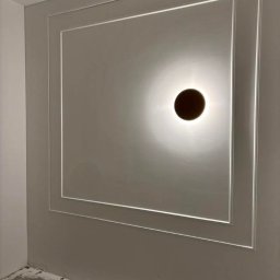 KRIS-BUD - Szara ściana z dekoracyjną ramą i okrągłym oświetleniem punktowym. Minimalistyczny design, wykończenie wnętrz w nowoczesnym stylu.