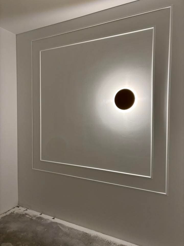 Szara ściana z dekoracyjną ramą i okrągłym oświetleniem punktowym. Minimalistyczny design, wykończenie wnętrz w nowoczesnym stylu.