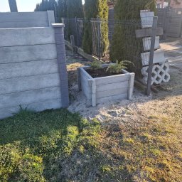 Usługi Ogulno Budowlane - Nowoczesne ogrodzenie panelowe z betonową podmurówką imitującą drewno, betonowa donica z roślinami, elementy kostki brukowej o ażurowym wzorze oparta o siatkę.