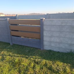 Usługi Ogulno Budowlane - Nowoczesne ogrodzenie panelowe z elementami imitującymi drewno i kamień, wkomponowane w zielony trawnik. Widok na dom w tle.