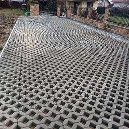 Firma Usługowa Marek Kołodziej - Szara, ażurowa kostka na podjeździe, widok z góry. W tle dom z balkonem i ogrodzenie z kamiennymi słupkami. Realizacja na posesji.