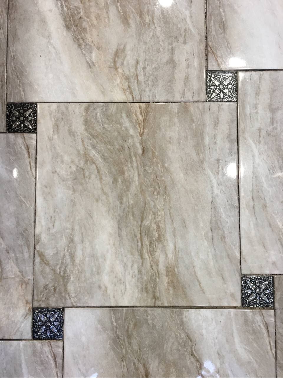 Beżowe płytki imitujące marmur, ułożone w prostokątnym wzorze z dekoracyjnymi, ciemnymi wstawkami w narożnikach. Widok z góry, oświetlenie górne.