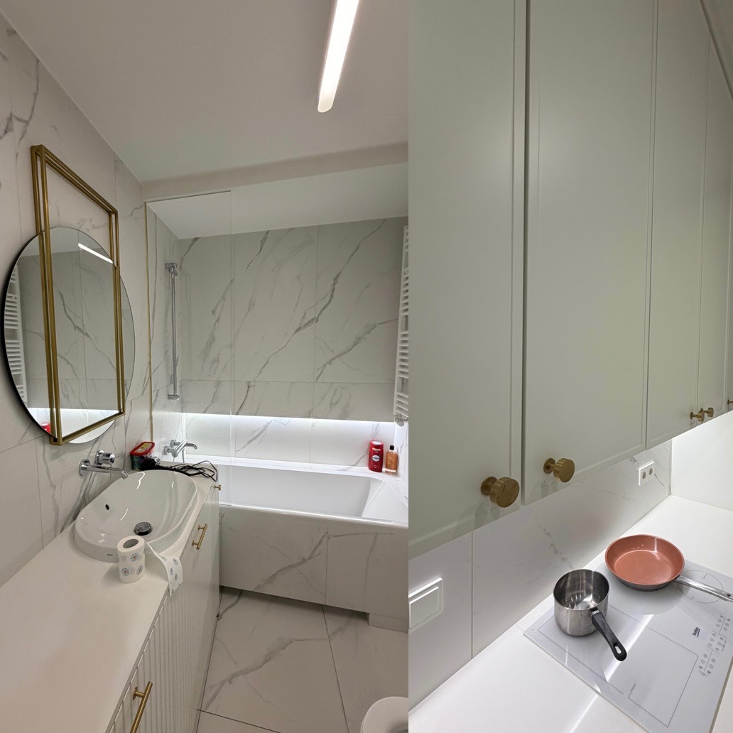 Nowoczesna łazienka z wanną i umywalką na tle marmurowych płytek, połączona z aneksem kuchennym z białymi szafkami i płytą indukcyjną. Złote akcenty.