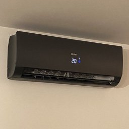 COOLBIX Tomasz Kulbicki - Czarny klimatyzator Haier na ścianie, wyświetlający temperaturę 20 stopni. Nowoczesny design, minimalistyczne wnętrze, widok z dołu.