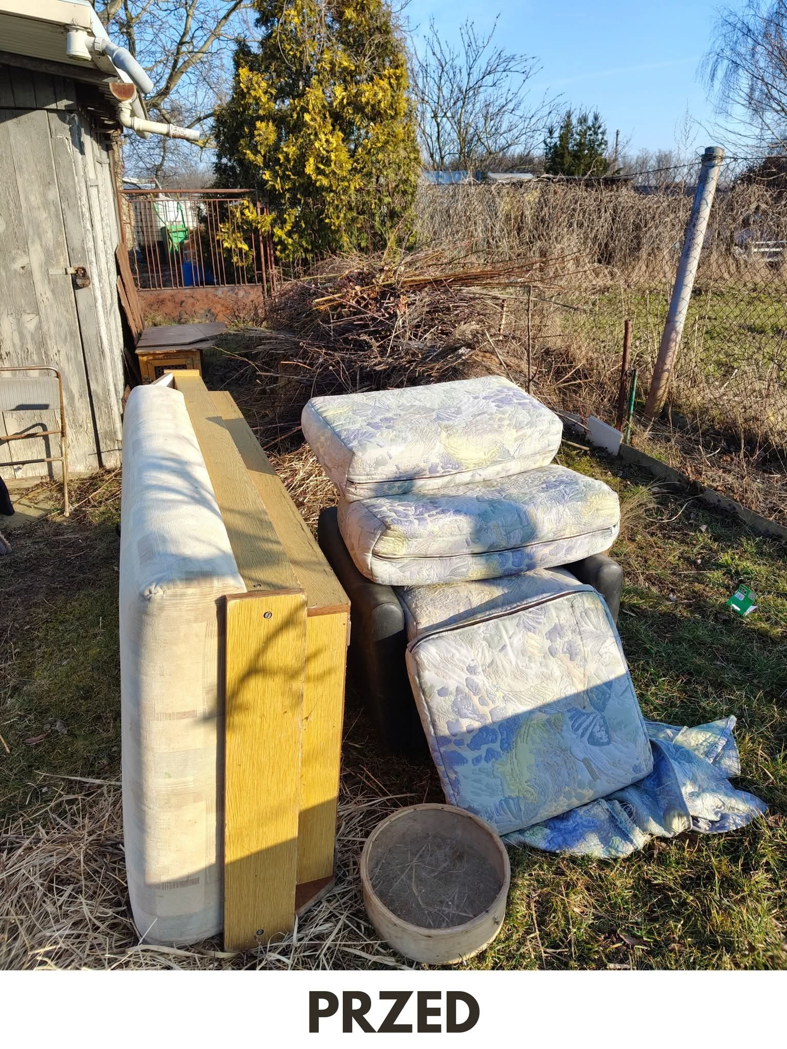 Stare meble i gałęzie na trawie, widok przed opróżnianiem posesji. W tle szopa i drzewa, słoneczny dzień. Fotografia z napisem 'PRZED' na dole kadru.