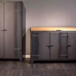 BGślusarnia - Metalowa szafa i komoda w stylu industrialnym, z drewnianym blatem, zdobione nitami i metalowymi okuciami, na tle szarej ściany i ciemnej podłogi.