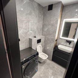LUX-FREE - Wykończona łazienka w szarościach z pralką Haier, podświetlanym lustrem i umywalką nablatową. Nowoczesny design z płytkami imitującymi marmur.