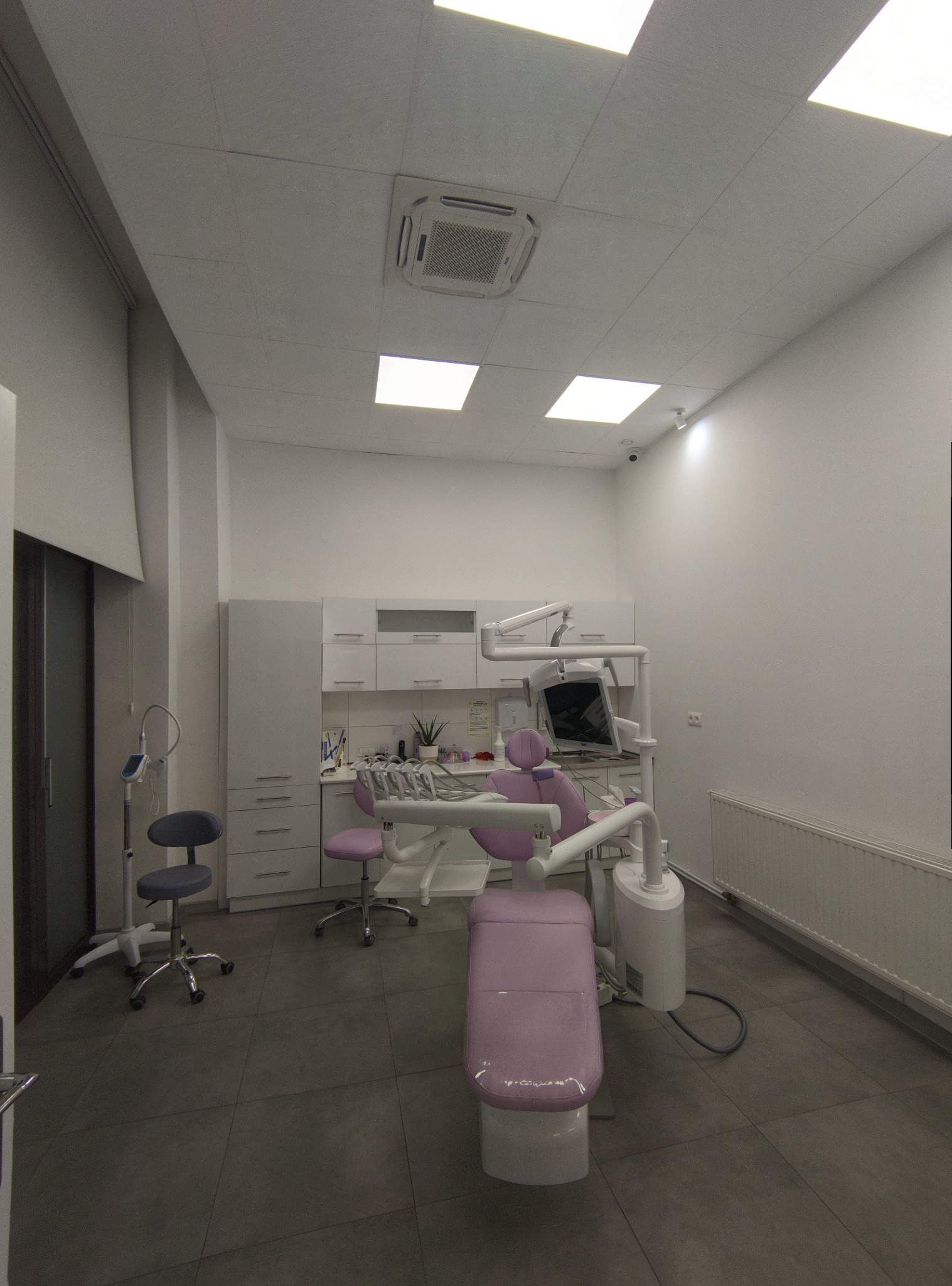 Klimatyzacja kasetonowa w gabinecie usługowym: biała jednostka w suficie podwieszanym, równomierne rozprowadzenie powietrza, widok na stanowisko dentystyczne.