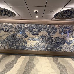 Jakub Szyptur - Ściana wyłożona dekoracyjnymi, ręcznie malowanymi płytkami ceramicznymi w odcieniach błękitu i bieli, przedstawiającymi sceny mitologiczne z motywami morskimi.