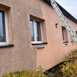 ENTOM TOMASZ NOWAK - Częściowo umyta, różowa elewacja budynku z oknami. Widoczna drabina oparta o ścianę. Efekt czyszczenia elewacji, kontrast brudnej i czystej powierzchni.
