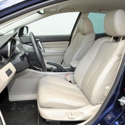 Piotr Kozłowiecki - Wnętrze niebieskiego samochodu z jasną, skórzaną tapicerką. Widoczne przednie fotele, deska rozdzielcza i kierownica. Czyste i zadbane wnętrze pojazdu.