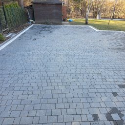Brukodnowa - Wyłożona szara kostka brukowa z białą obwódką na posesji w Siemianowicach Śląskich. Widoczny fragment trawnika, budynek gospodarczy i ogrodzenie.