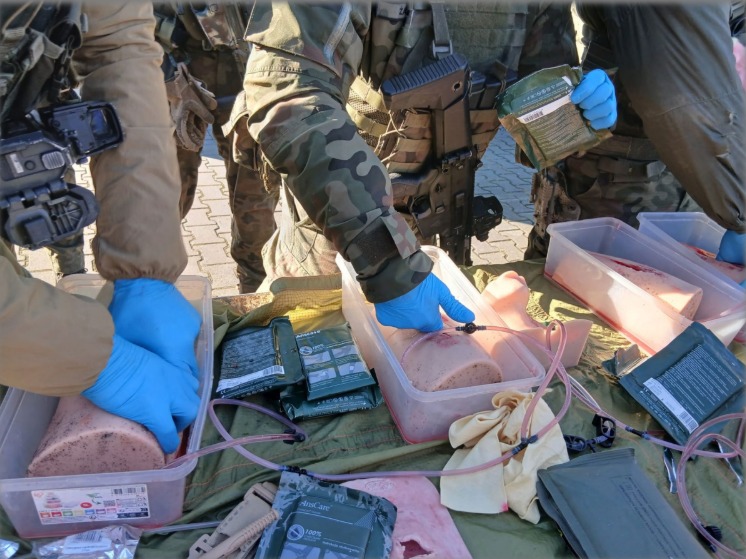 Szkolenie z pierwszej pomocy: żołnierze w mundurach ćwiczą udzielanie pomocy na manekinach z symulacją ran, używając specjalistycznych opatrunków i sprzętu medycznego.