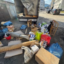 Jakub Marczak - Opróżnianie mieszkania: Załadowany śmieciami i meblami samochód dostawczy na tle miejskiej zabudowy. Widoczne worki, kartony i inne przedmioty przeznaczone do utylizacji.