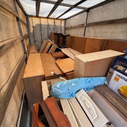 Jakub Marczak - Wnętrze skrzyni ładunkowej wypełnionej meblami i sprzętami AGD, gotowymi do transportu. Widoczna torba podróżna i kartony z odkurzaczami.