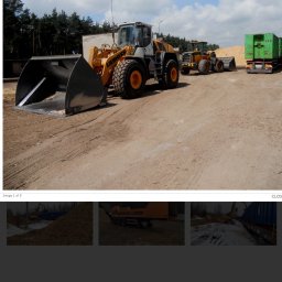 Kas-Bud przedsiębiorstwo ogólno budowlane. - Żółto-szara ładowarka Liebherr na placu budowy, w tle inne maszyny i drzewa. Sprzęt gotowy do pracy przy niwelacji terenu lub wywozie ziemi.