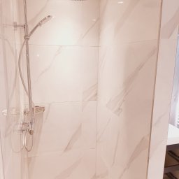 B&K FLEX SP. Z O.O. - Nowoczesna kabina prysznicowa z deszczownicą i marmurowymi płytkami w odcieniach bieli i beżu. Widoczny odpływ liniowy i półka na kosmetyki.