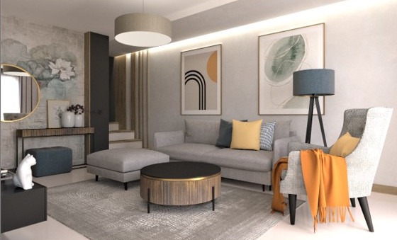 Jasne wnętrze salonu z szarą sofą, okrągłym stolikiem kawowym i fotelami. Na ścianach wiszą obrazy w ramach. Dekoracyjny motyw kwiatowy na ścianie.