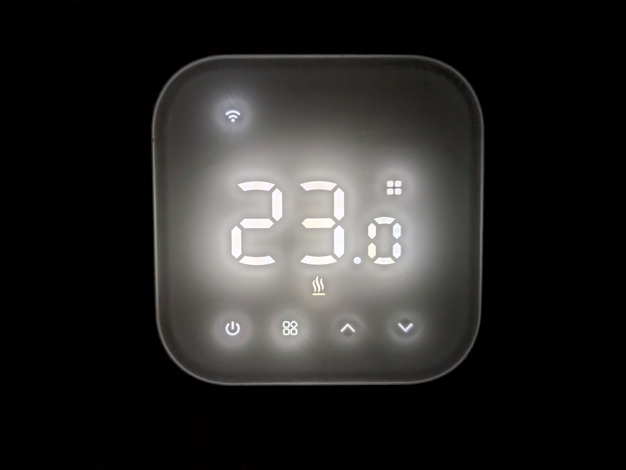 Panel sterowania inteligentnego domu z wyświetlaczem temperatury 23.0°C, ikoną Wi-Fi i przyciskami funkcyjnymi na czarnym tle. Nowoczesny design.