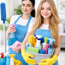 Easyclen - Dwie uśmiechnięte kobiety w niebieskich fartuchach trzymające wiadro i pojemnik ze środkami czystości w jasnym wnętrzu.