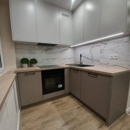 MIROSŁAW SKUBISZ - Nowoczesna kuchnia w odcieniach szarości i beżu z marmurowym backsplashiem, oświetleniem LED pod szafkami i drewnopodobną podłogą. Minimalistyczny design.