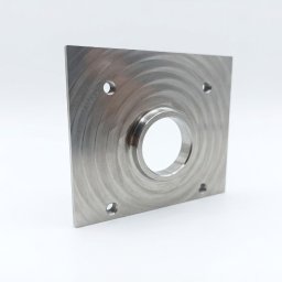 SON - MET PATRYK MORAWSKI - Metalowy, kwadratowy element z centralnym otworem i czterema mniejszymi otworami w rogach, wykończony z widocznymi śladami obróbki na jasnym tle.