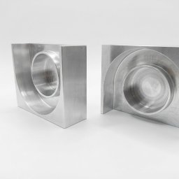 SON - MET PATRYK MORAWSKI - Dwa precyzyjnie obrobione, srebrne, metalowe bloki z okrągłymi wgłębieniami, ukazujące dokładność i jakość wykonania na białym tle. Widoczne ślady obróbki.